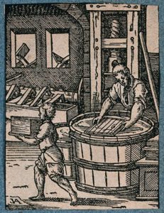 A woodcut print showing a man making paper; his apprentice carrying away the finished sheets.