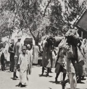 A black and white photograph showing prisoners in chains carrying luggage