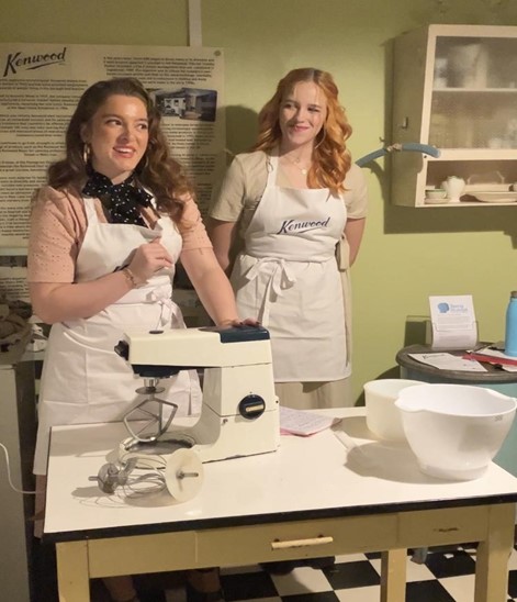 A photograph of two female actors demonstrating a Kenwood mixer