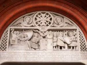 A decorative carving from the French Protestant Church in London showing a group of refugees in a boat and King Edward VI signing the 1550 Royal charter giving freedom of religious observance to French protestants/